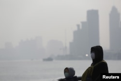 FILE - People wear protective masks near the Bund in Shanghai, China, Jan. 19, 2016. China's top court in January reaffirmed a record fine on six firms for discharging toxic waste acids into two rivers in Jiangsu province.