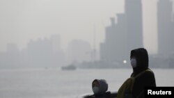 FILE - People wear protective masks near the Bund during a polluted day in Shanghai, China, Jan. 19, 2016. 