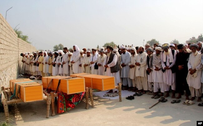 FILE - Afghan men offer funeral prayers near the bodies of civilians killed in a NATO airstrike, on the outskirts of Jalalabad, east of Kabul, Afghanistan, Oct. 5, 2013.