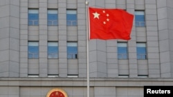 Bendera China berkibar di dekat lambang nasional China di Pengadilan Menengah Rakyat No. 2 Beijing, 11 September 2020. (Foto: Reuters)