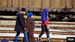 A Syrian family walk back down the tracks away from Macedonia after being told the border won’t open today. (Jamie Dettmer for VOA)