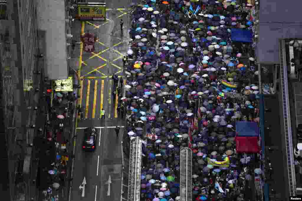 Ribuan demonstran pro-demokrasi berbaris di jalan pada Juli 2013 untuk menuntut hak pilih universal dan mendesak Kepala Eksekutif Hong Kong Leung Chun-ying untuk mundur. (Reuters/Tyrone Siu)