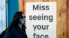 A woman in a face mask walks by a sign posted on a boarded up restaurant in San Francisco, California, April, 1, 2020, during the novel coronavirus outbreak.