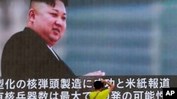 FILE - A man takes a photo of a TV news program showing an image of North Korean leader Kim Jong Un, in Tokyo, Japan, Aug. 6, 2017.