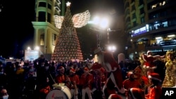 Members of a band wearing Santa Claus costumes perform during the illumination of a giant Christmas tree at the launch of Christmas festivities at Sassine square in the Achrafieh district of Beirut, Lebanon, Dec. 7, 2021. 