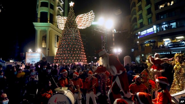Members of a band wearing Santa Claus costumes perform during the illumination of a giant Christmas tree at the launch of Christmas festivities at Sassine square in the Achrafieh district of Beirut, Lebanon, Dec. 7, 2021.