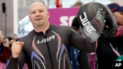 FILE - The driver of United States USA-1, Steven Holcomb, acknowledges the crowd after the team won the bronze medal during the men's four-man bobsled competition final at the 2014 Winter Olympics, Feb. 23, 2014, in Krasnaya Polyana, Russia.