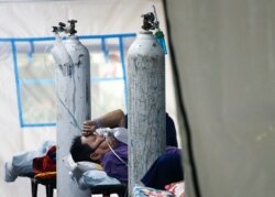 Seorang pasien COVID-19 bernapas dengan masker non-rebreather di tenda darurat sebuah rumah sakit di Jakarta, 24 Juni 2021. (Foto: REUTERS/Ajeng Dinar Ulfiana)