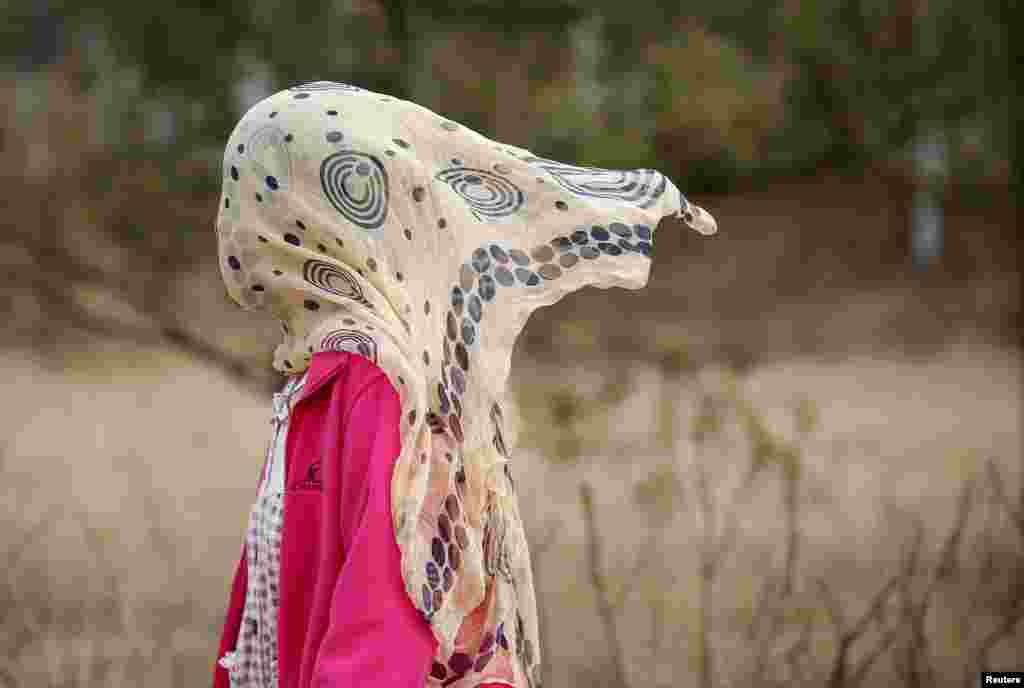 A woman protect herself from pollution by covering her face with a scarf, while walking in a park in Beijing, China.