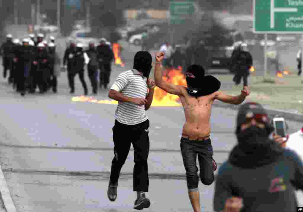 Riot police firing tear gas chase Bahraini anti-government protesters throwing petrol bombs in Manama, Bahrain.