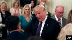El presidente Donald Trump (centro) saluda a las personas que llegan a una cena para líderes evangélicos en la Casa Blanca el 27 de agosto de 2018.