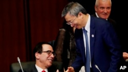 美国财政部长姆努钦与中国银行行长易纲星期六（2019年6月8日）在日本20国财长与央行行长会议期间握手。