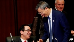 China's Central Bank Governor Yi Gang shakes hands with U.S. Treasury Secretary Steve Mnuchin, left, during the G20 Finance Ministers and Central Bank Governors Meeting Saturday, June 8, 2019, In Fukuoka, Japan.