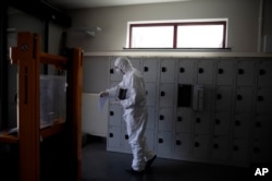 A worker in protective gear carries an urn of ashes of a COVID-19 victim at the Pontes crematorium and funeral center in Wilrijk, Belgium, April 3, 2020. An extra 200 COVID-related cremations had been done since the start of the week.