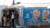 FILE - Youths stand outside a makeshift shop near murals of former South African president and anti-apartheid hero Nelson Mandela in Soweto, Johannesburg, South Africa.