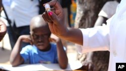 FILE - A health worker prepares to administer an oral cholera vaccination to a child at a camp for displaced survivors of cyclone Idai in Beira, Mozambique, April 3, 2019. 