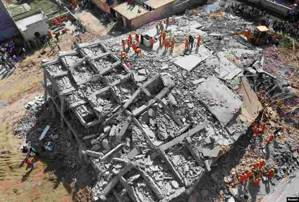 Rescue workers look for survivors amidst the rubble at the site of a collapsed residential building at Shah Beri village in Greater Noida, India.