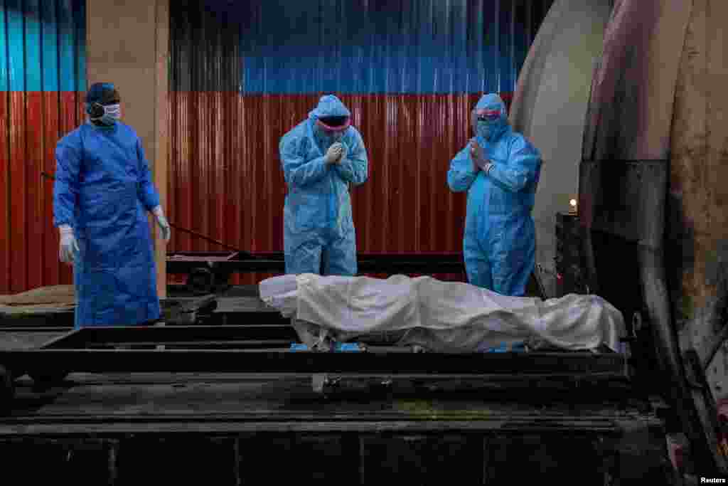 Relatives pray before the cremation of a woman, who died due to the coronavirus disease (COVID-19), at a crematorium in New Delhi, India.
