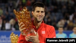 Novak Djokovic dari Serbia memegang piala setelah mengalahkan David Ferrer dari Spanyol dalam final Mubadala World Tennis Championship di Abu Dhabi, Uni Emirat Arab (28/12). (AP/Kamran Jebreili)