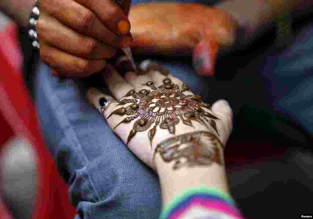 A young girl gets her hand decorated with henna paste at a marketplace ahead of the Eid al-Adha festival in Srinagar, India, Sept. 23, 2015.