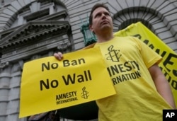 FILE - William Butkus of Amnesty International holds up a sign outside the 9th U.S. Circuit Court of Appeals in San Francisco, Feb. 7, 2017.