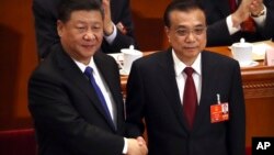 Chinese President Xi Jinping, left, shakes hands with Premier Li Keqiang after Li was re-elected as Premier during a plenary meeting of China's National People's Congress (NPC) at the Great Hall of the People in Beijing, March 18, 2018. 