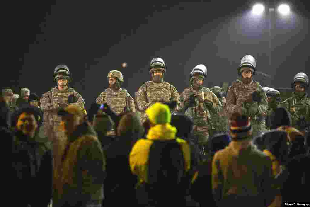 National Guard soldiers stand watch over the Ferguson Police Department as protesters chant in front of them during a third night of protests in Ferguson, Missouri, Nov. 26, 2014.