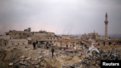 ສະມະຊິກຂອງກອງກຳລັງທີ່ຈົງຮັກພັກດີຕໍ່ປະທານາທິບໍດີຂອງ ຊີເຣຍ ທ່ານ Basha al-Assad ຢືນກັບພົນລະເຮືອນຄົນໜຶ່ງ ຢູ່ກອງຊາກຫັກພັງຂອງໂຮງແຮມ Carlton ໃນເມືອງ Aleppo ເຂດທີ່ລັດຖະບານຄວບຄຸມ. ຊີເຣຍ. 17 ທັນວາ, 2016.