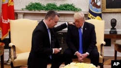 El presidente Donald Trump reza con el pastor americano Andrew Brunson en el despacho oval de la Casa Blanca. Octubre 13, 2018.