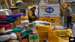 2021年11月16，一家私人快递公司的工人在北京一栋住宅公寓楼附近的一个取件点整理堆积的包裹。（美联社照片）