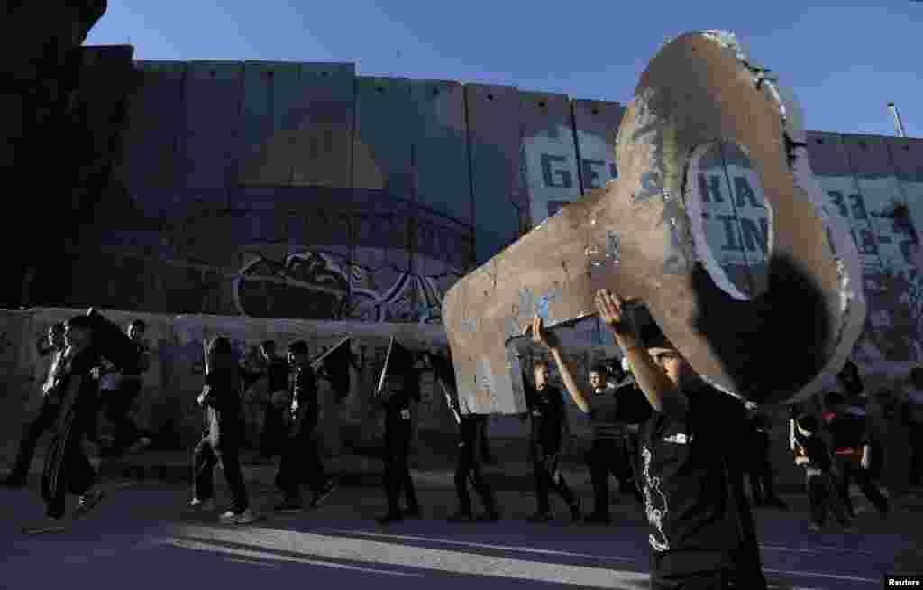 A Palestinian boy holds a large cutout of a key as he walks with others along the controversial Israeli barrier during a rally ahead of the 66th anniversary of Nakba (disaster) in the West Bank town of Bethlehem.