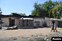 FILE - Women walk by homes destroyed by Boko Haram militants in Bama, Borno State, Nigeria.