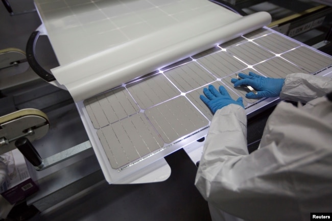 FILE - A production operator checks a panel at a solar panel factory in Oregon, Jan. 15, 2018.