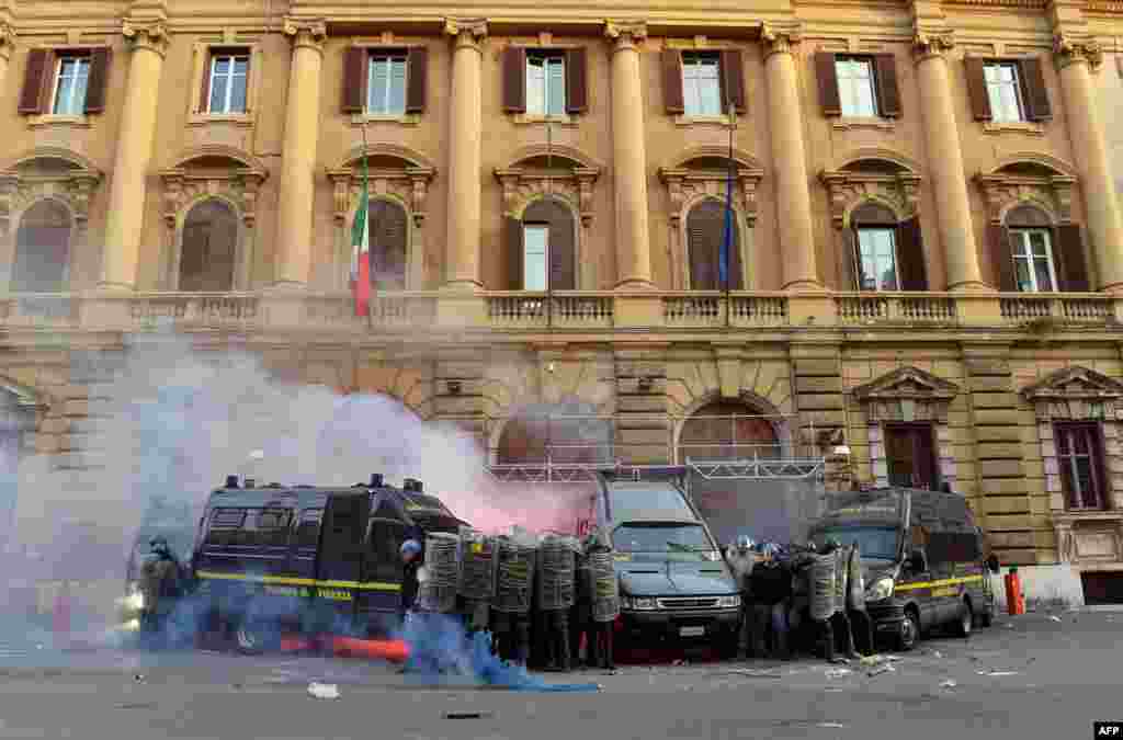 Members of the Guardia di Finanza protect themselves as they stand in front of the Economy ministry during clashes on the sidelines of an anti-austerity protest in Rome, Italy.