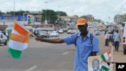 A street vendor sells Ivorian flags and portraits of Ivory Coast President Alassane Ouattara at a market in Yamoussoukro on May 20, 2011, before his investiture ceremony which is due to be held on May 21, 2011.