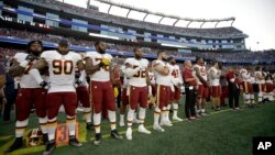 Los jugadores de los Washington Redskins permanecen de pie durante la interpretación del himno nacional ante del primer partido de la pretemporada de la NFL ante los Patriots de Nueva Inglaterra el jueves, 9 de agosto de 2018 en Foxborough, Massachusetts.