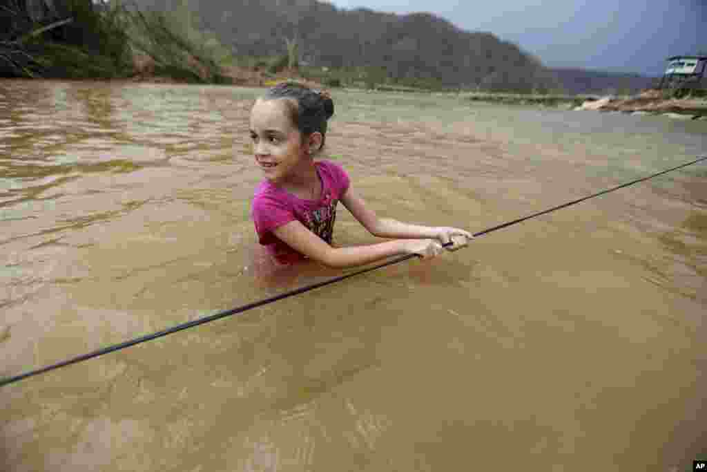 Ruby Rodriguez, 8, looks back at her mother as she wades across the San Lorenzo Morovis river with her family, since the bridge was swept away by Hurricane Maria, in Morovis, Puerto Rico, Sept. 27, 2017.