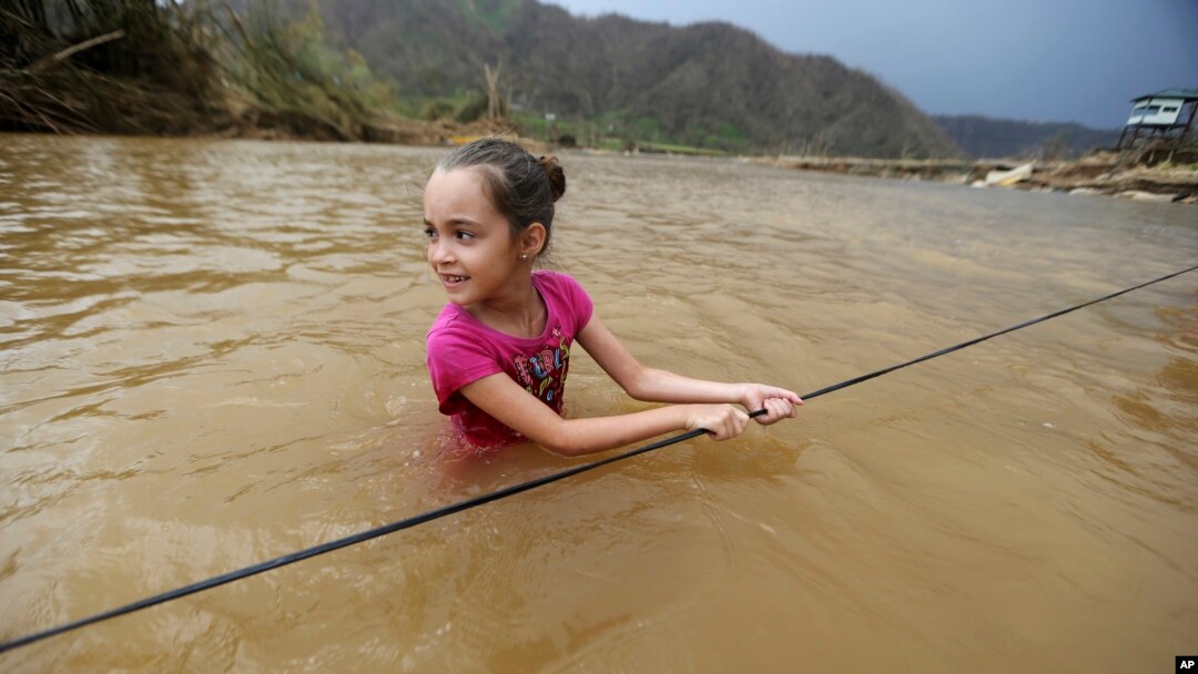 Ruby Rodriguez, de ocho años, cruza el río San Lorenzo Morovis con el agua a la cintura debido a la caída del puente destruido durante el paso del huracán María.