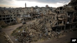 A car drives through a devastated part of the old city of Homs, Syria, Jan. 16, 2018.