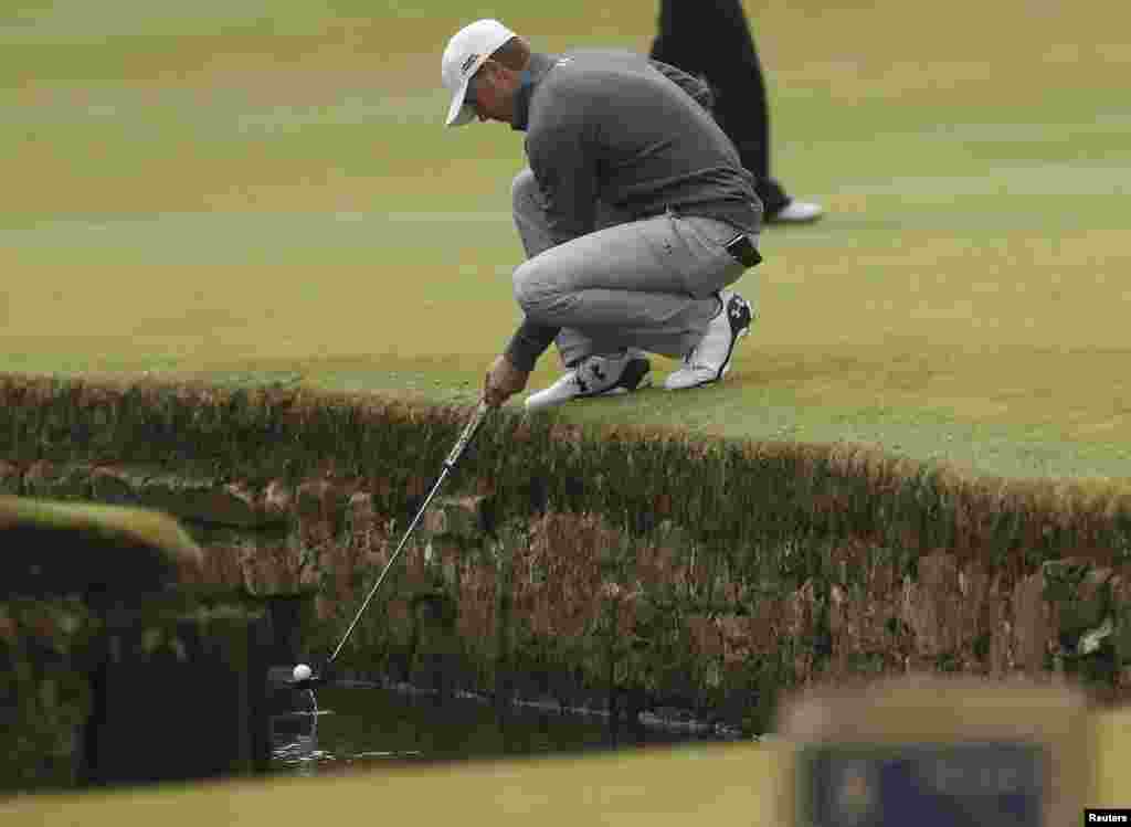 Jordan Spieth of the U.S. retrieves his ball from the Swilcan Burn on the first hole during a practice round ahead of the British Open golf championship on the Old Course in St. Andrews, Scotland, July 15, 2015.