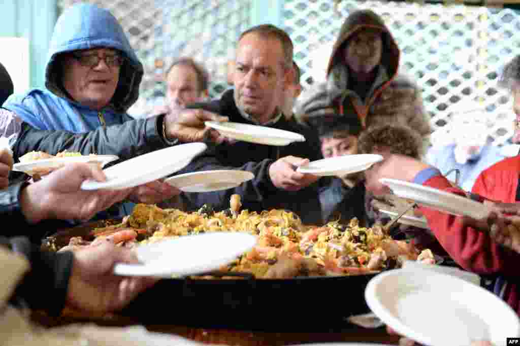 People enjoy a plate of a paella dish offered as a Christmas gift for poor people by a restaurant owner in Bordeaux, southwestern France, Dec. 25, 2014.