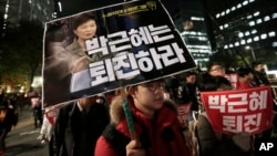 FILE - A South Korean protester carries a placard showing images of South Korean President Park Geun-hye and Choi Soon-sil, top left, during a rally calling for Park to step down, Nov. 2, 2016.