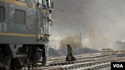 A Tibetan woman walks across the tracks at the Lhasa railway station in Lhasa, capital of southwest China's Tibet Autonomous Region March 4, 2006. The Qinghai-Tibet railway, which runs from Xining in Qinghai province to Lhasa, will be opened to cargo trai