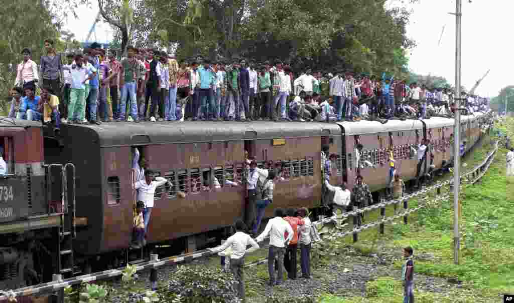 Indian devotees travel atop of a crowded train as they head to attend the Dada Ji Dham fair which coincides with the Guru Purnima festival at Khandwa, Madhya Pradesh state, India.