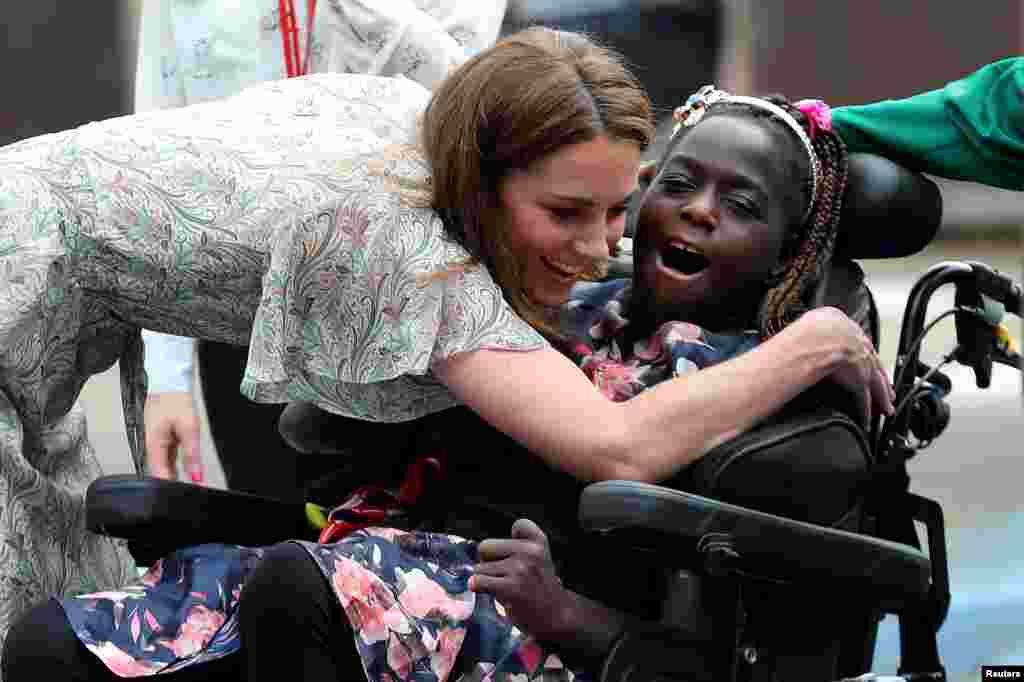Britain&#39;s Catherine, Duchess of Cambridge, hugs a girl in a wheelchair as she joins a photography workshop with Action for Children in Kingston upon Thames.