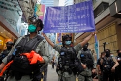 Police display a public announcement banner showing the warning to protesters in Causeway Bay before the annual handover march in Hong Kong, Wednesday, July 1, 2020.