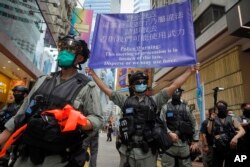 Police display a public announcement banner showing the warning to protesters in Causeway Bay before the annual handover march in Hong Kong, Wednesday, July 1, 2020.