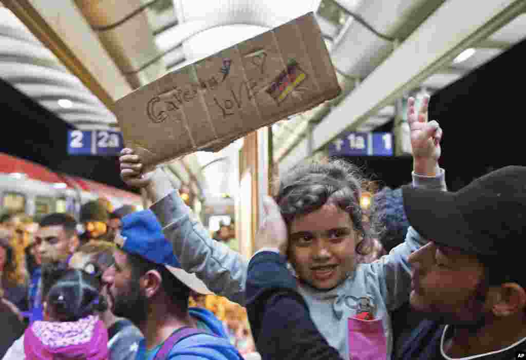 A migrant girl holds a sign expressing her love to Germany as she arrives at the train station in Saalfeld, central Germany, Sept. 5, 2015.