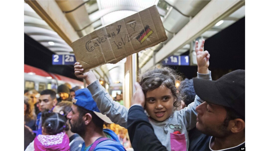 A migrant girl holds a sign expressing her love to Germany as she arrives at the train station in Saalfeld, central Germany, Sept. 5, 2015.