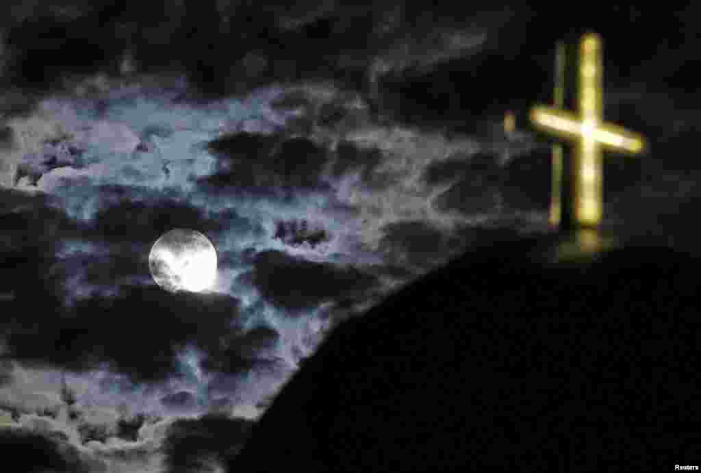 그리스 산토리니섬의 한 교회 십자가 위로 달이 떴다.